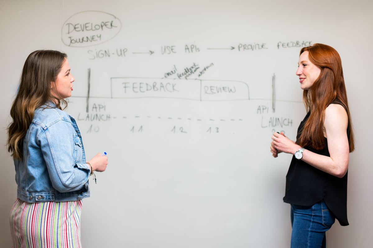 Two women discussing development work at a whiteboard.